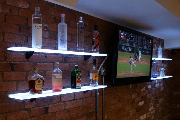 4.5" LED floating shelves installed on exposed brick, lighting up a home bar's liquor collection next to the big screen, perfect for game day