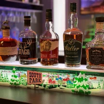 Custom South Park LED liquor display with premium whiskey bottles on white shelf with snowy town graphics